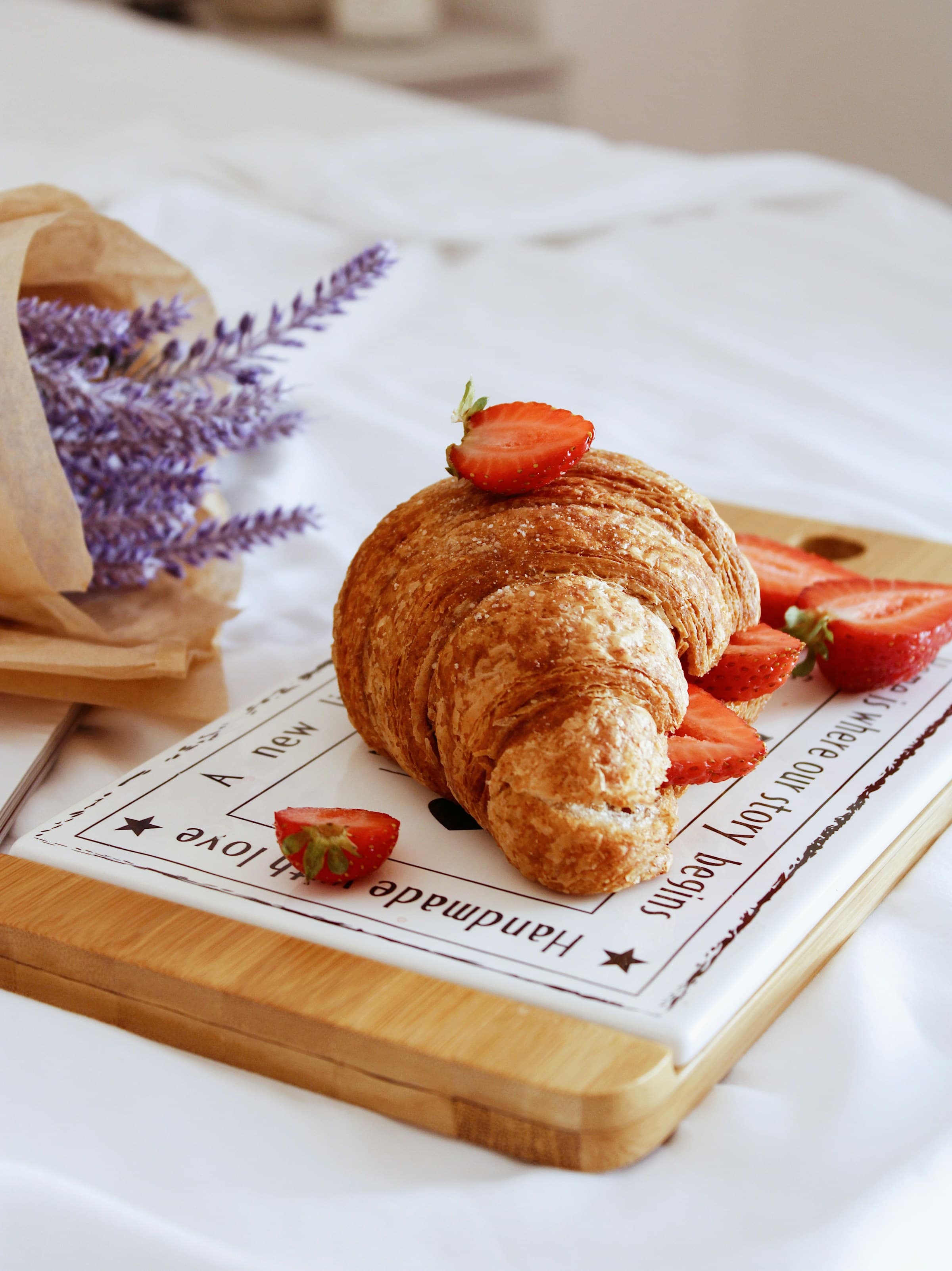 Golden croissant with fresh strawberries on a cutting board