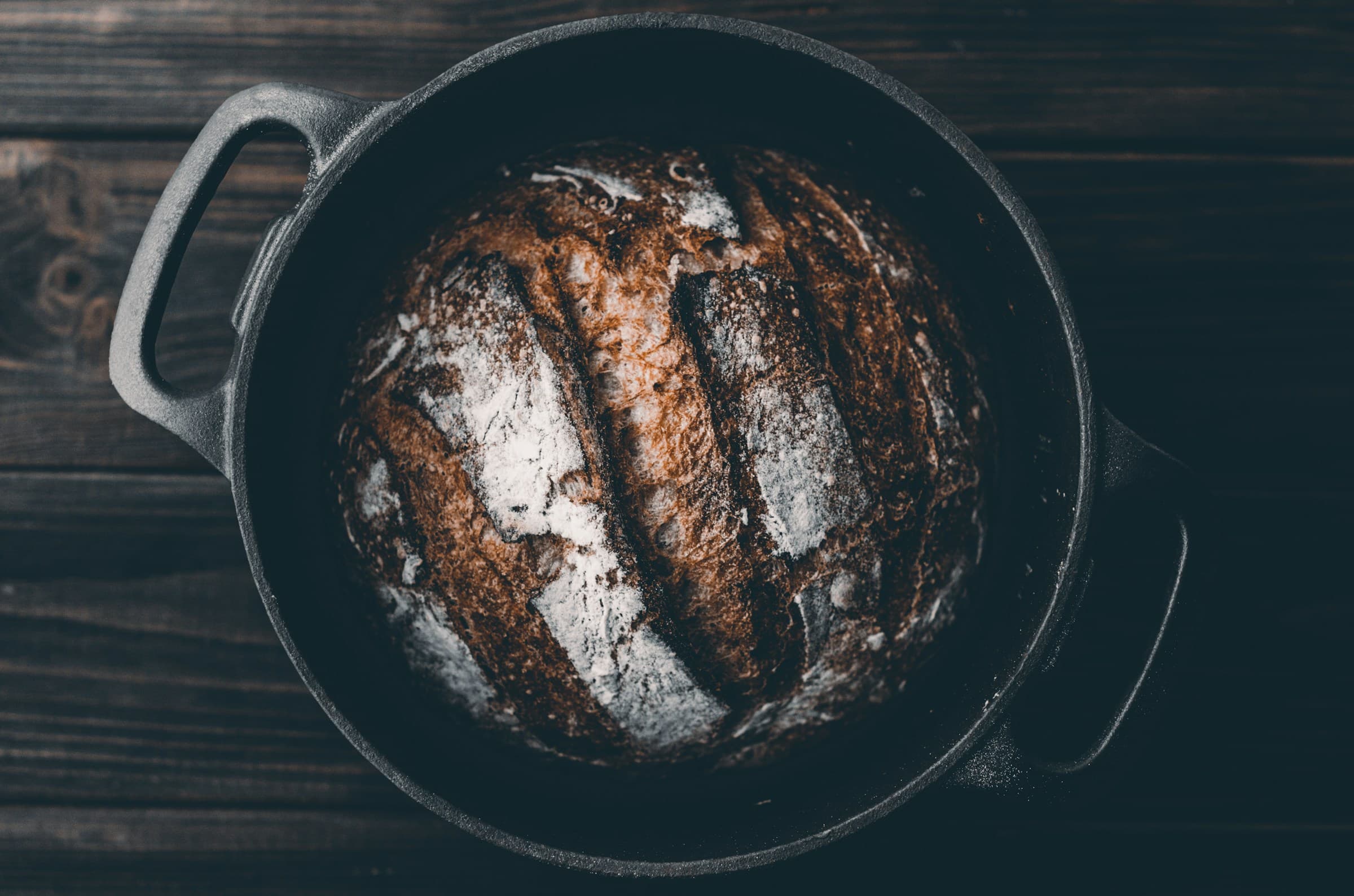 Dark crusty sourdough loaf in a cast iron Dutch oven