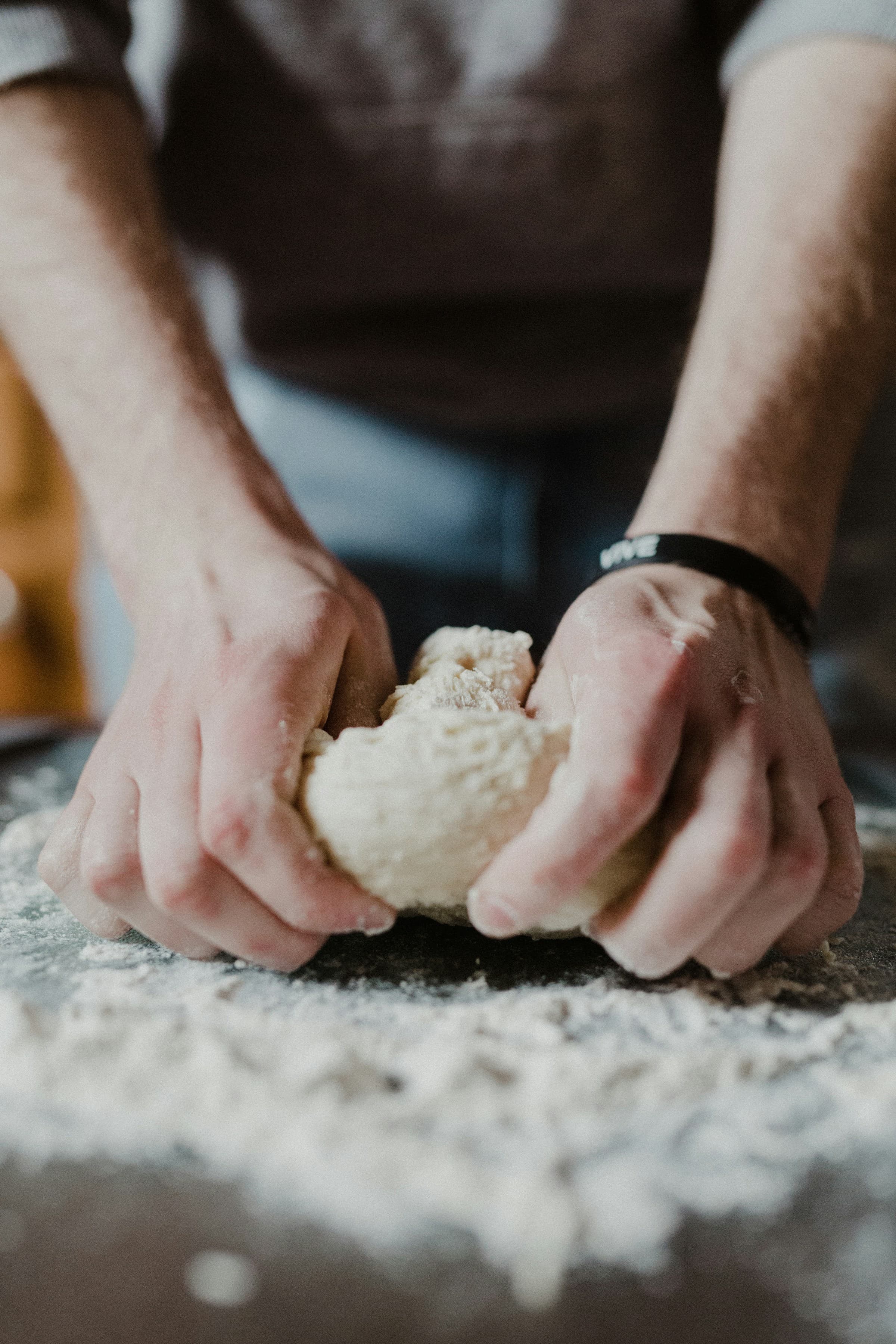 Baker's hands kneading dough on a floured surface