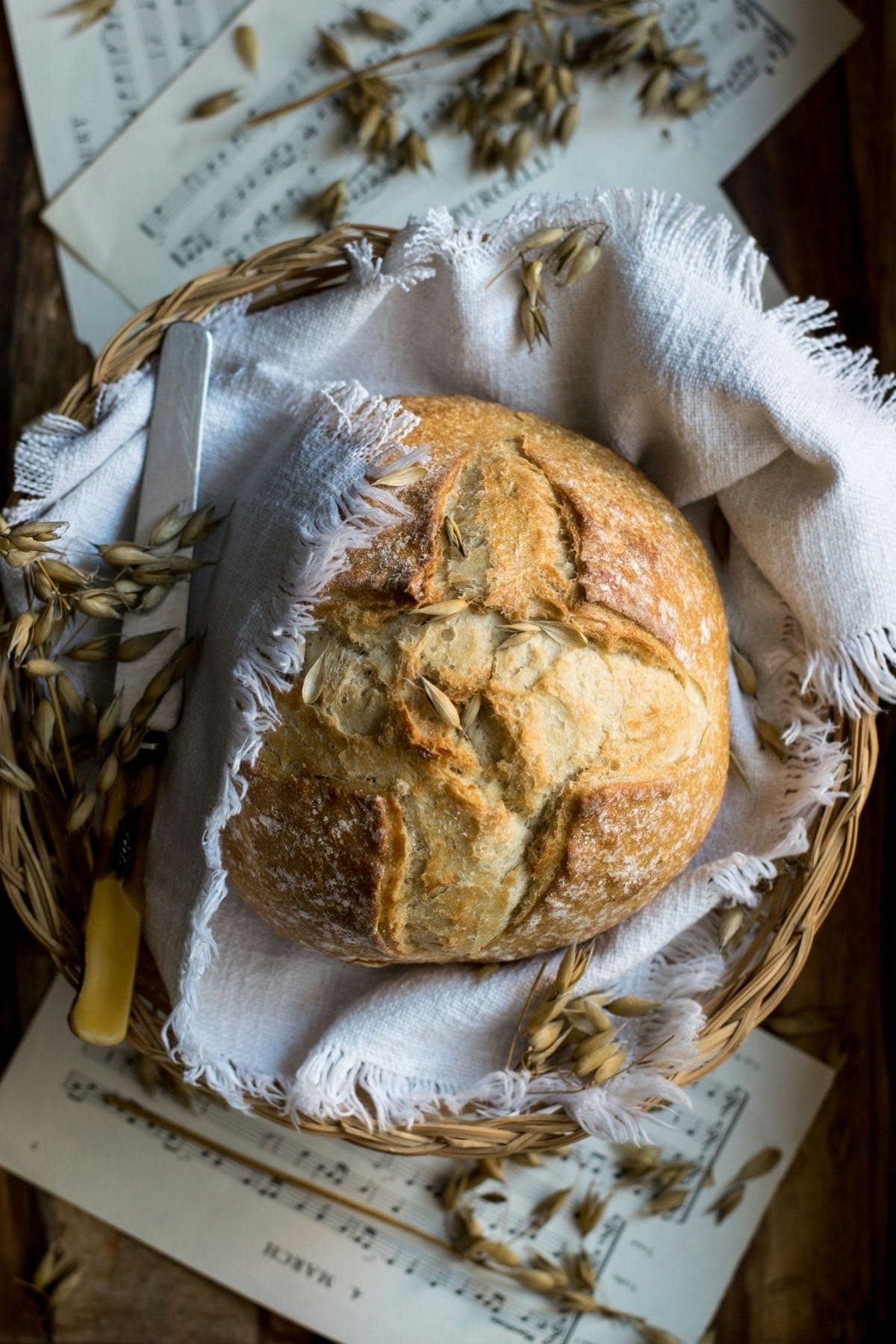 Rustic bread loaf nestled in a wicker basket with wheat stalks